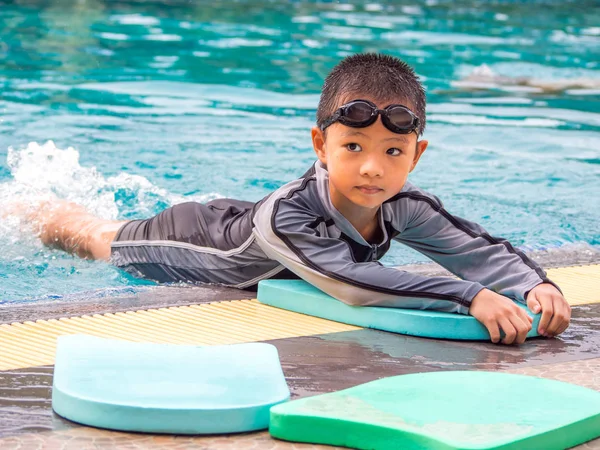 Asian boy swimming with the board in the pool — Stock Photo, Image