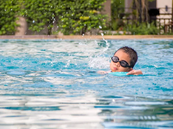 Ásia menino natação com o bordo no o piscina — Fotografia de Stock