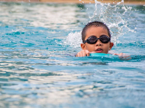 Ásia menino natação com o bordo no o piscina — Fotografia de Stock