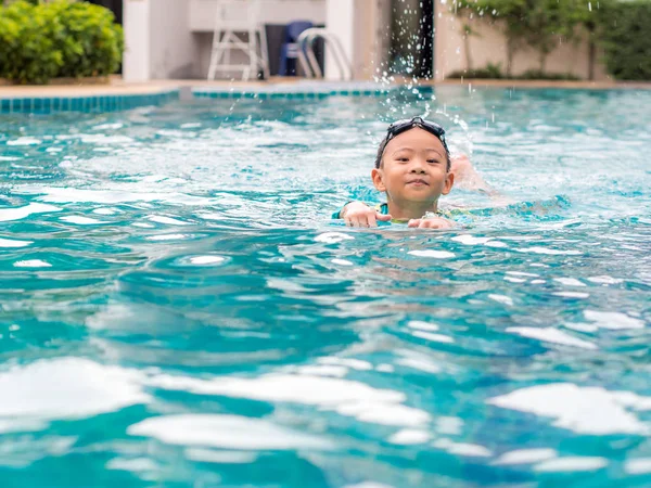 Asiatisch junge schwimmen mit die board im die pool — Stockfoto