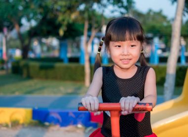 Mutlu çocuk, bir tahterevalli üzerinde oynayan Asya bebek çocuk 