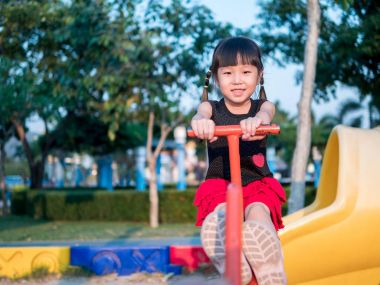 Mutlu çocuk, bir tahterevalli üzerinde oynayan Asya bebek çocuk 