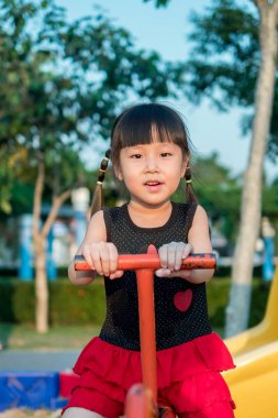 Mutlu çocuk, bir tahterevalli üzerinde oynayan Asya bebek çocuk 