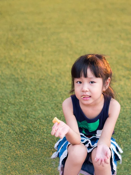 행복 한 아이, 잔디밭에는 쿠키를 먹는 아시아 아기 어린이 — 스톡 사진