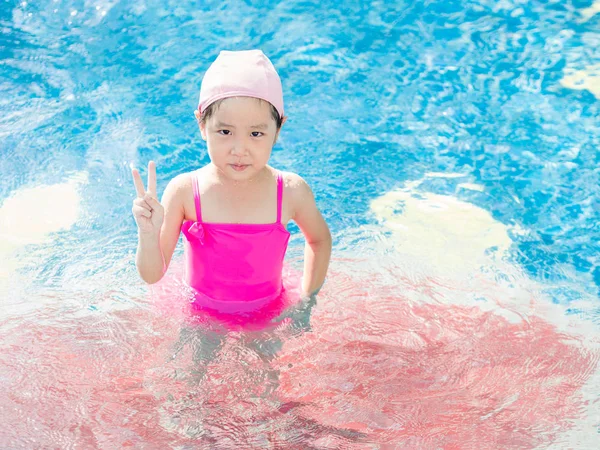 Menina asiática está jogando na piscina, dedos vitória — Fotografia de Stock