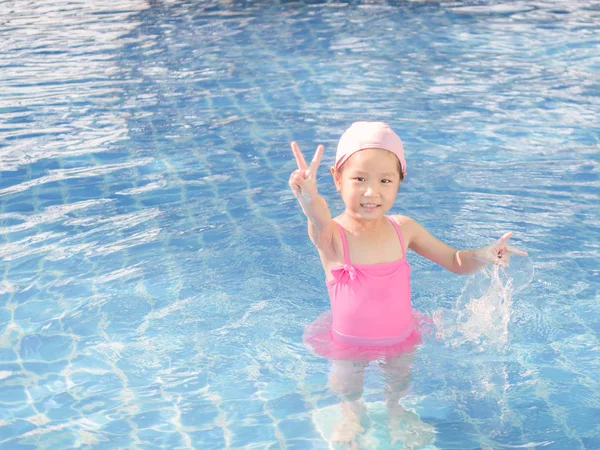 Menina asiática está jogando na piscina, dedos vitória — Fotografia de Stock