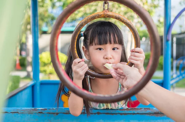 Азиатский ребенок играет на детской площадке, едят манго из anothe — стоковое фото