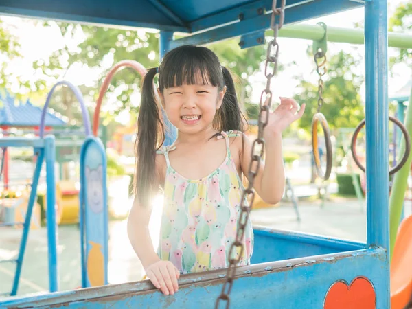Азиатский ребенок играет на детской площадке, в лучах заката — стоковое фото