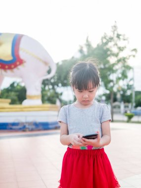 Asyalı çocuk kız oyun bahçesinde akıllı telefon