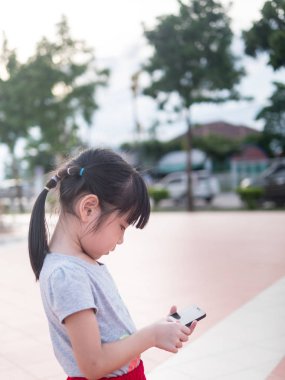 Asyalı çocuk kız oyun bahçesinde akıllı telefon