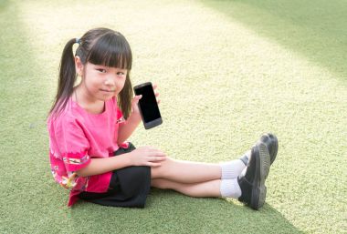 Asyalı çocuk kız oyun bahçesinde akıllı telefon