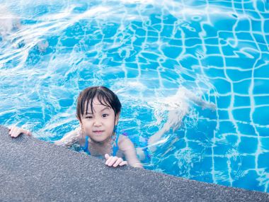 Asian girl is playing in the pool, raise one's eyebrows  clipart