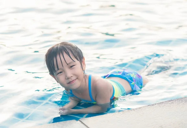 Asian girl is playing in the pool, laying down — Stock Photo, Image