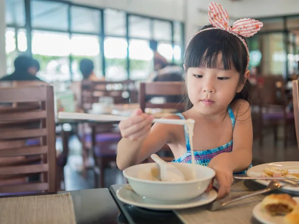 Çubuk ile lezzetli makarna yiyerek mutlu Asyalı çocuk