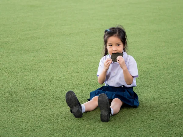 Счастливый азиатский ребенок ест вкусные нори водоросли, в саду — стоковое фото