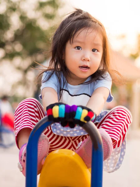 Счастливый азиатский ребенок на качелях в лучах заката — стоковое фото