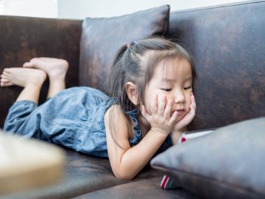 Güzel genç kız çocuk üzerinde bir kanepe evde izle bırakmasını