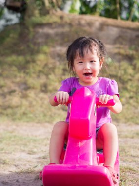 küçük asain kız oturup üzerinde sallanan at