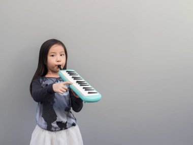 Küçük Asyalı çocuk oyun melodion, gri arka plan
