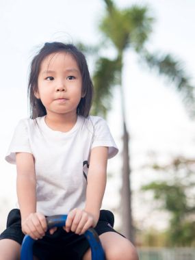 Beyaz t s giyen mutlu Asyalı çocuk üzerinde bir tahterevalli günbatımı ışık,