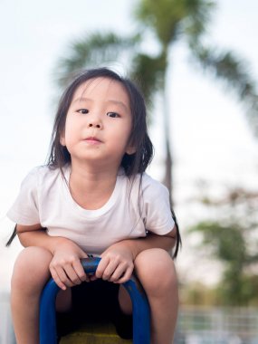 Beyaz t s giyen mutlu Asyalı çocuk üzerinde bir tahterevalli günbatımı ışık,