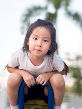 Beyaz t s giyen mutlu Asyalı çocuk üzerinde bir tahterevalli günbatımı ışık,