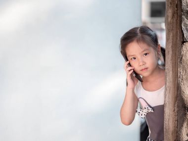 Asyalı kız duvarın arkasında saklanıyor kullanmak akıllı telefon 