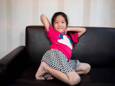 küçük Asyalı çocuk kız çocuk streç kendini kanepeye h sonra