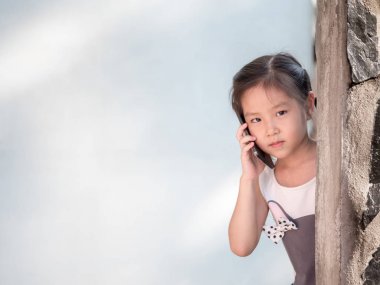Asyalı kız duvarın arkasında saklanıyor kullanmak akıllı telefon