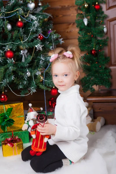 Meisje bij de kerstboom met speelgoed — Stockfoto