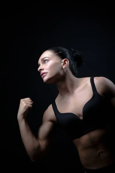 Sporty brunette girl on a black background in a swimsuit — Stock Photo, Image