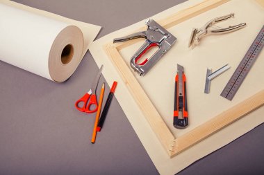 Sanatçı roll, tuval, zımba tabancası ve gri arka plan üzerinde diğer araçları için sedye üzerinde tuval