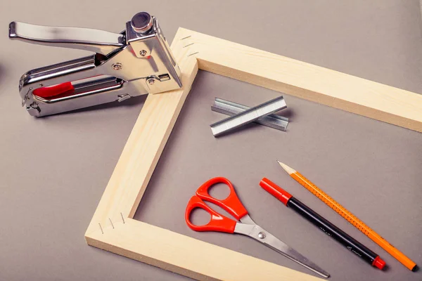 stretcher for canvas, staple gun and other tools on a gray background