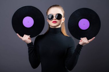 Güzel bir kız, onun güneş gözlüğü vinil kayıtları tutar. Gri bir arka plan üzerinde