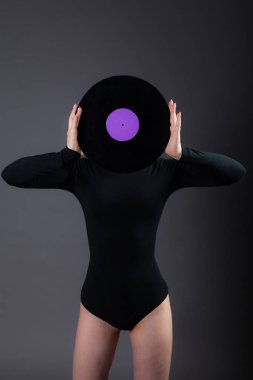 Kız bir vinil disk onun elinde tutan, yüzüne kapatır. Gri bir arka plan üzerinde fotoğraf stüdyosu