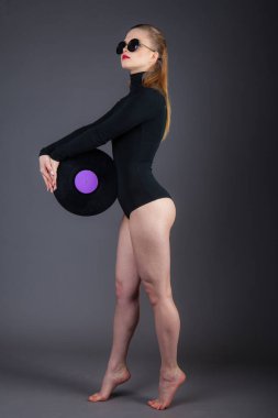 Güzel bir kız bir vinil disk güneş gözlüğü ile onun elinde tutuyor. 