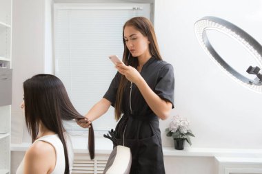 Kız kuaför senin telefonundaki fotoğrafı yapıyor. Blog ve sosyal ağlar için yaptıkları işlerin fotoğrafı.