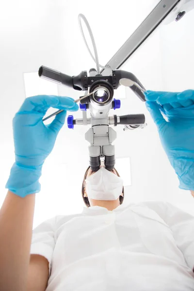 Une dentiste examine un microscope dentaire. Vue du bas . — Photo