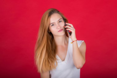 Güzel kızıl saçlı, gülümseyen bir kadın cep telefonuyla konuşuyor..