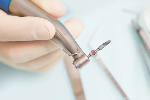 Durante a operação, o dentista segura ferramentas de implantação com um implante de titânio — Fotografia de Stock
