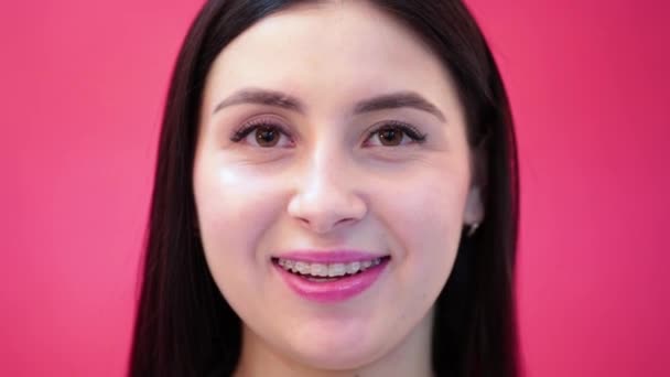 Ung kvinna med tandställning ler och slickar sina läppar — Stockvideo