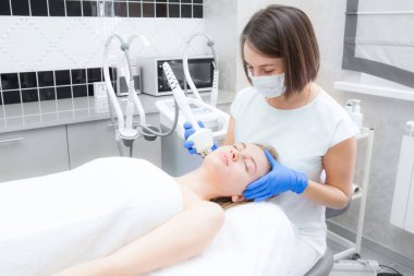 Güzellik uzmanı bir güzellik salonunda yatan kusursuz kadın yüzü için rf-lift işlemi yapıyor. Hasta yüz masajı yaptırıyor. Cilt tazeleme ve kırışıklık giderme.