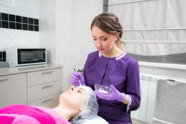 Yüz soyma maskesi, kaplıca güzellik tedavisi, cilt bakımı. Güzellik salonunda güzellik uzmanı bir kadının yüz bakımını alıyor.