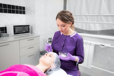 Yüz soyma maskesi, kaplıca güzellik tedavisi, cilt bakımı. Güzellik salonunda güzellik uzmanı bir kadının yüz bakımını alıyor.