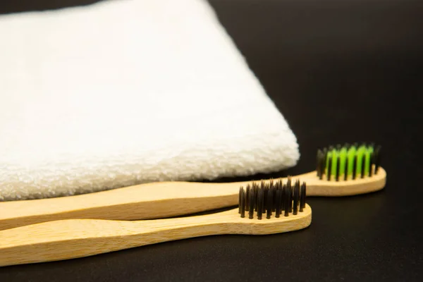 Bamboo toothbrushes with a white towel on a black background. Biodegradable natural bamboo toothbrush. Eco-friendly, zero waste, dental care.