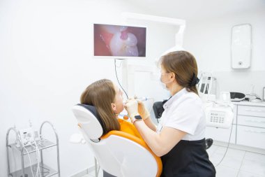 Dişçi, tedavi odasında intraoral kamera kullanarak hastanın dişlerini teşhis etti.