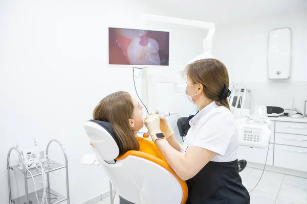 Стоматолог диагностирует зубы пациента с помощью внутриротовой камеры в кабинете — стоковое фото