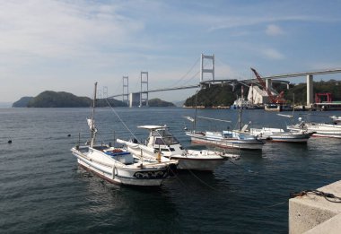 Arka planda Kurushima Köprüsü olan Oshima Adası 'na yanaşan tekneler, Shimanami Kaido, Japonya