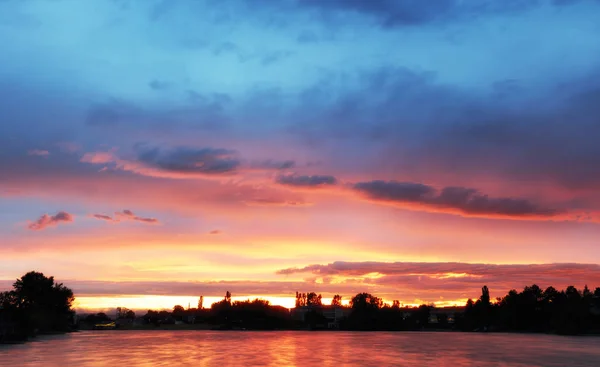 Un paisaje fantástico. La dramática puesta de sol sobre un lago, rayos — Foto de Stock