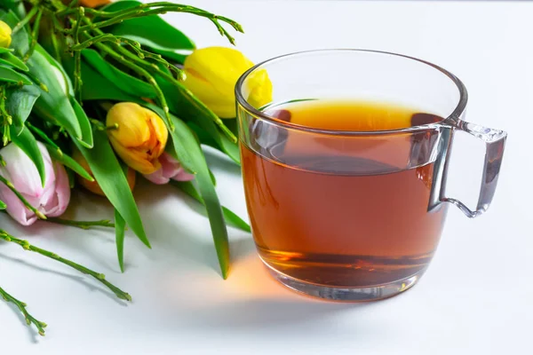 Una taza de té en una mesa con ramo de flores de tulipán — Foto de Stock